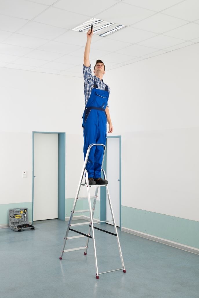 Male Electrician On Ladder Installing Ceiling Light 687x1030